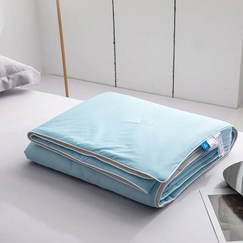 The doona folded on a bed, showing the stitched quilting and the grey piped edge